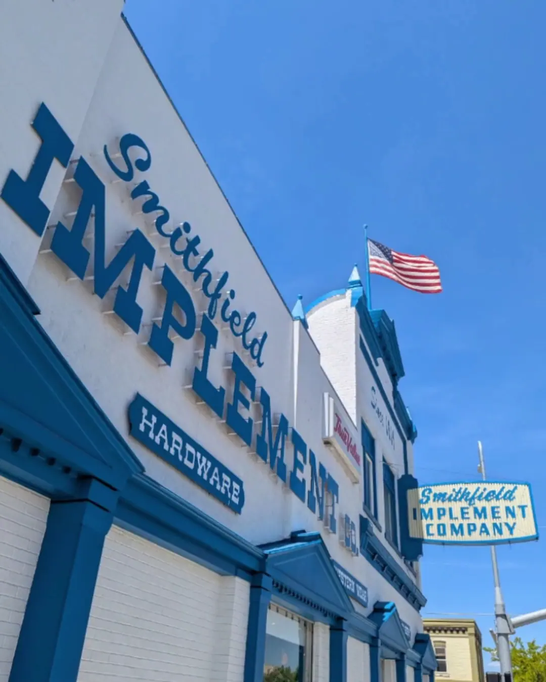 The Smithfield Implement sign lettering on the corner of the building, with a flag