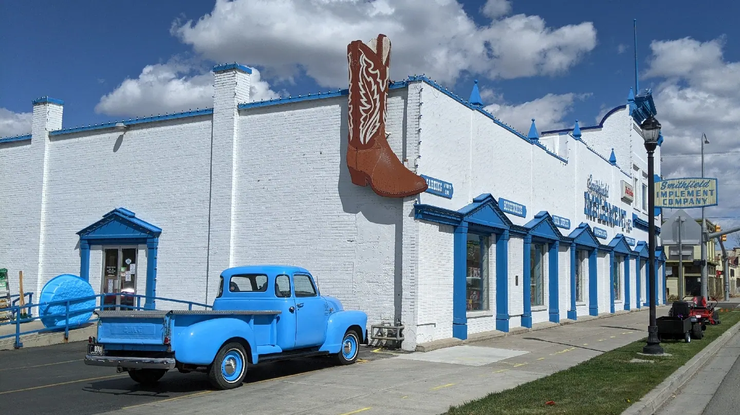 The side of the store with the big boot sign and a blue pickup truck at the curb